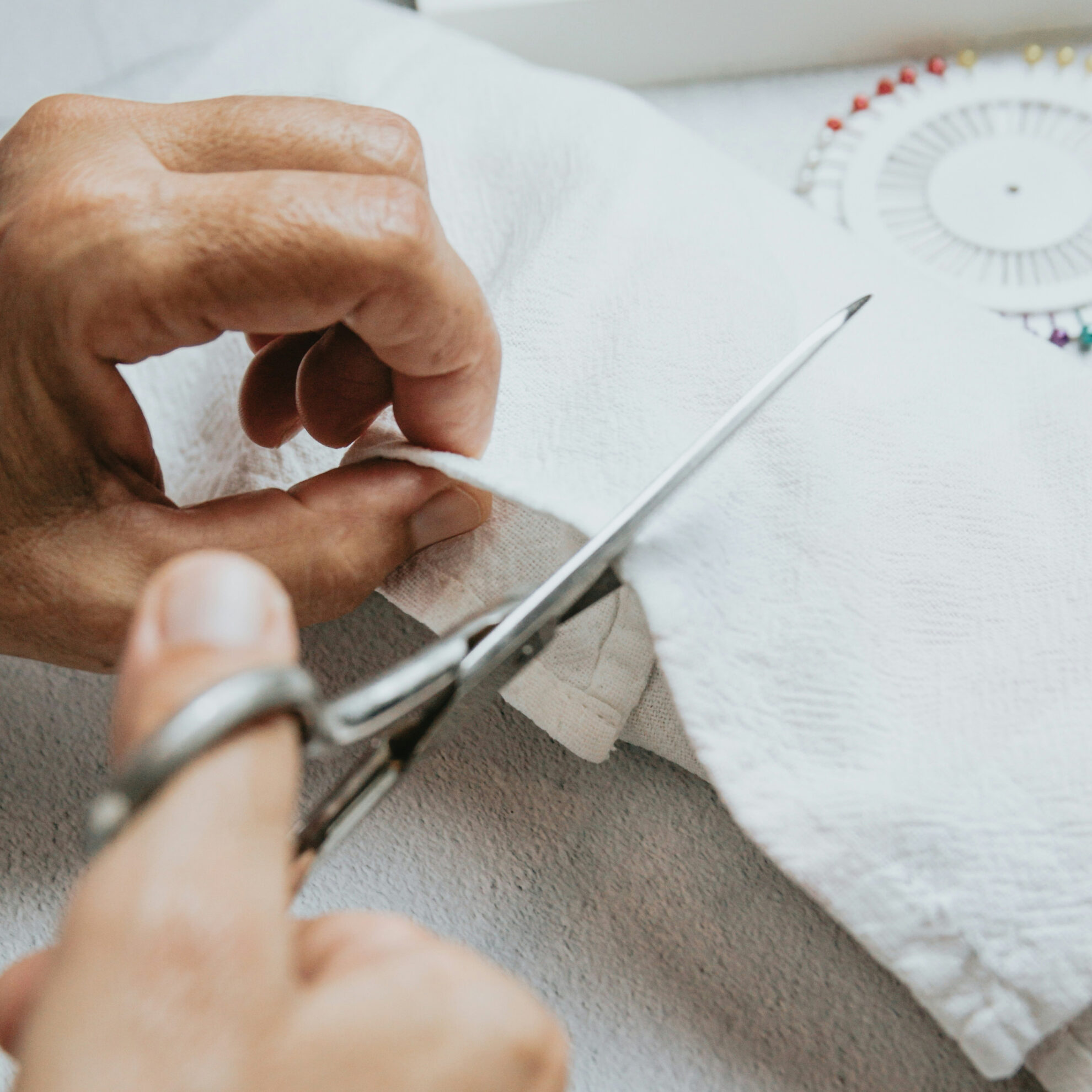 Bild mit Händen die ein Stück Stoff zuschneiden
